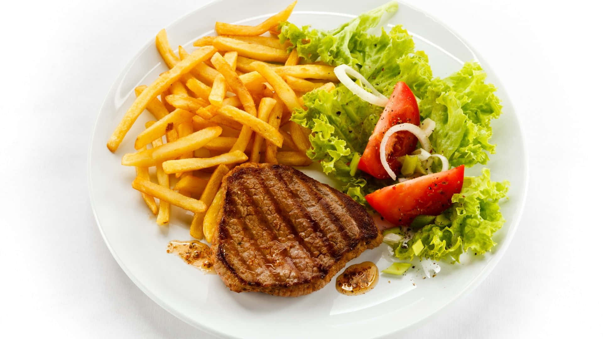 A Plate With Steak, Fries And Salad