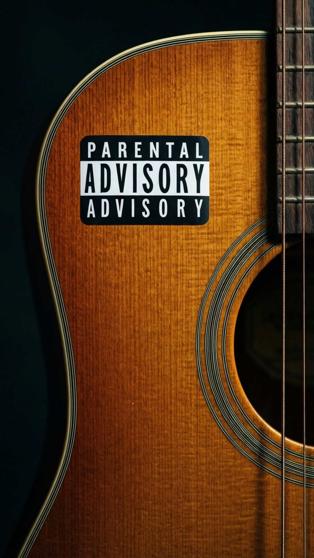 Parental advisory sticker on a guitar, close-up, wood grain.
