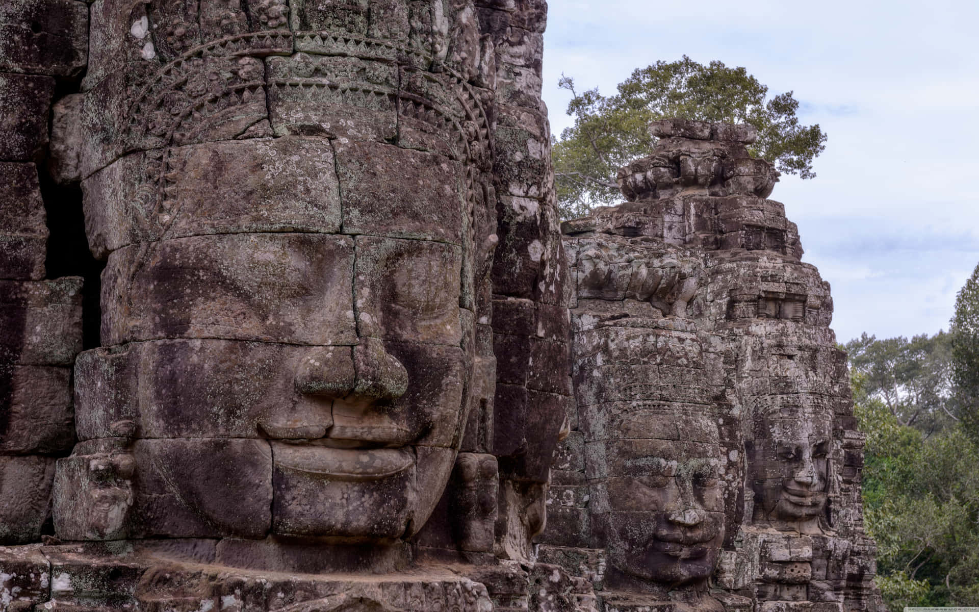 Statuedi Volti Di Pietra Ad Angkor Thom. Sfondo