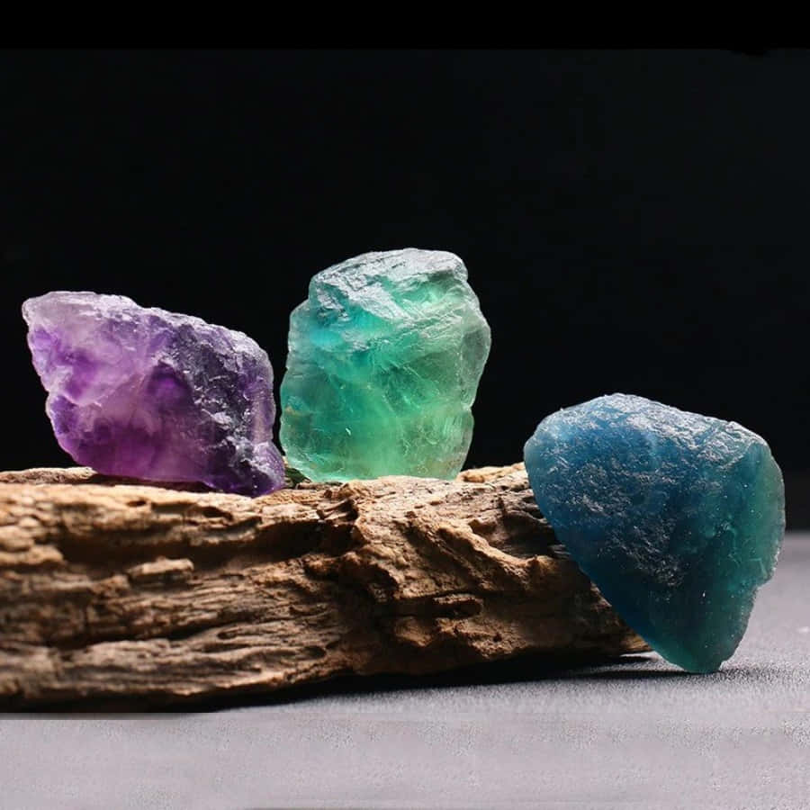 Three Different Colored Stones On A Piece Of Wood