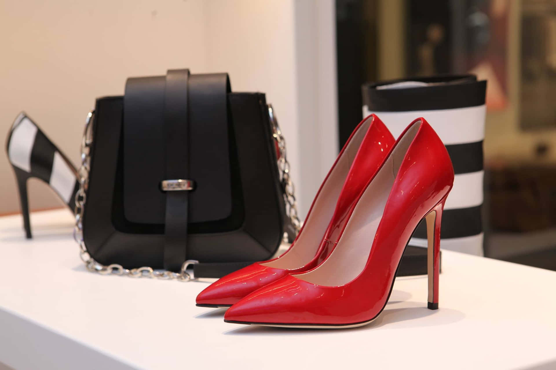 Red High Heel Pumps With Black Purse On Display