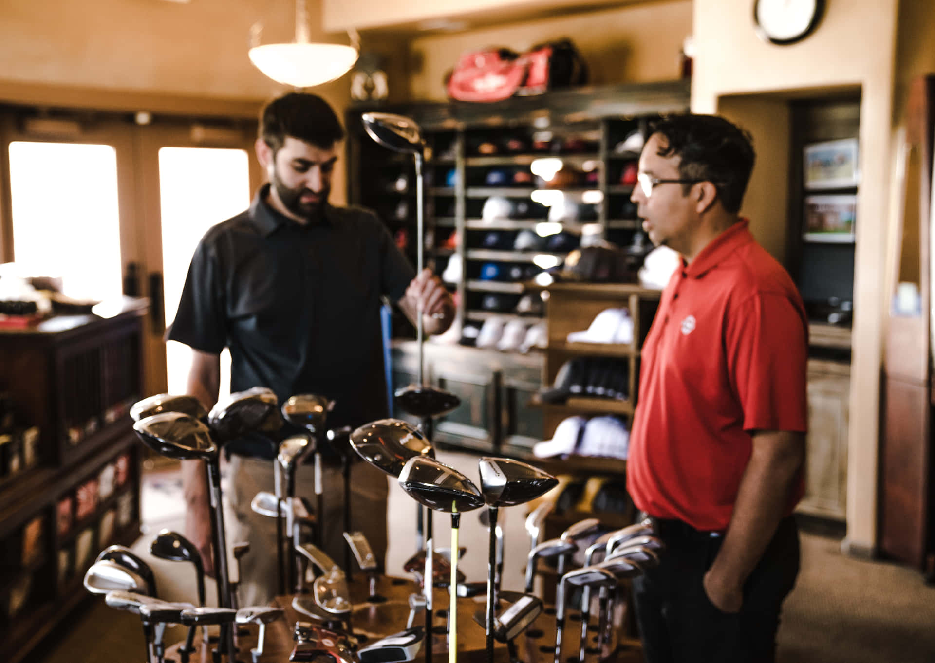 Two Men Standing In A Golf Shop Looking At Golf Clubs