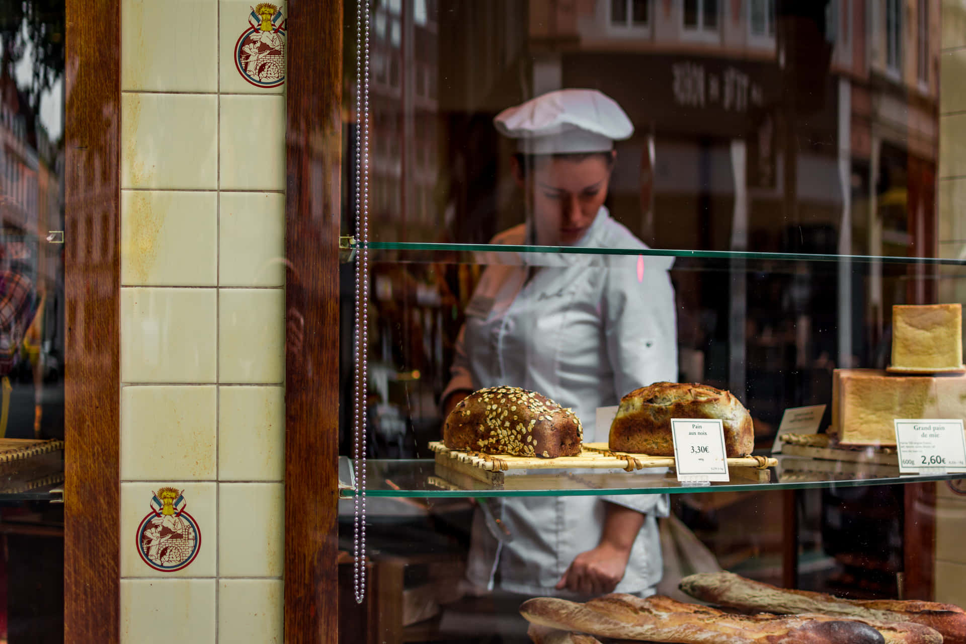 A Woman Is Standing In Front Of A Bakery Window