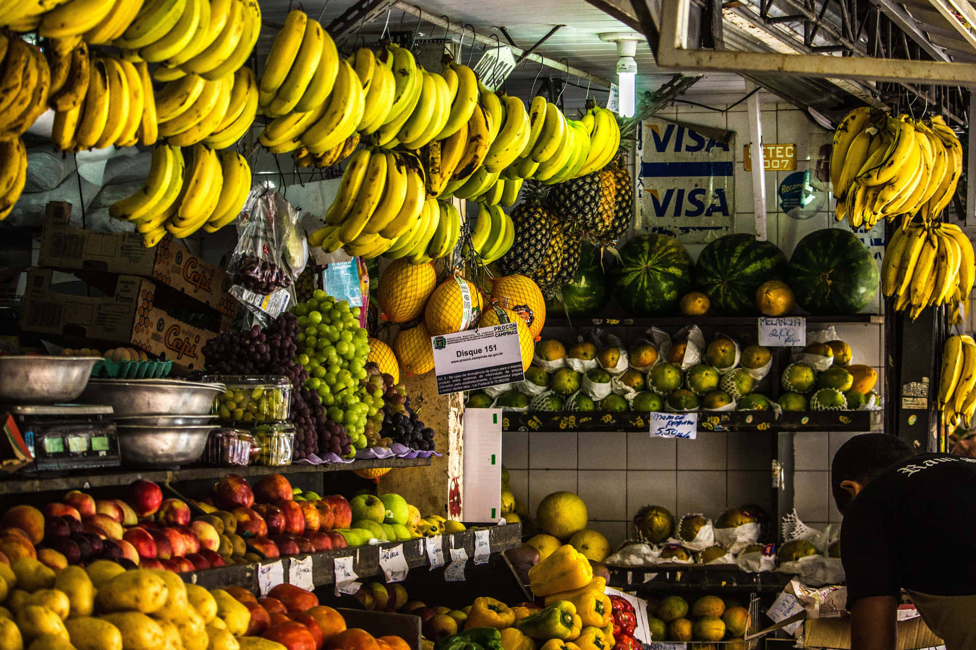 A Man Is Standing In A Market With A Lot Of Fruit