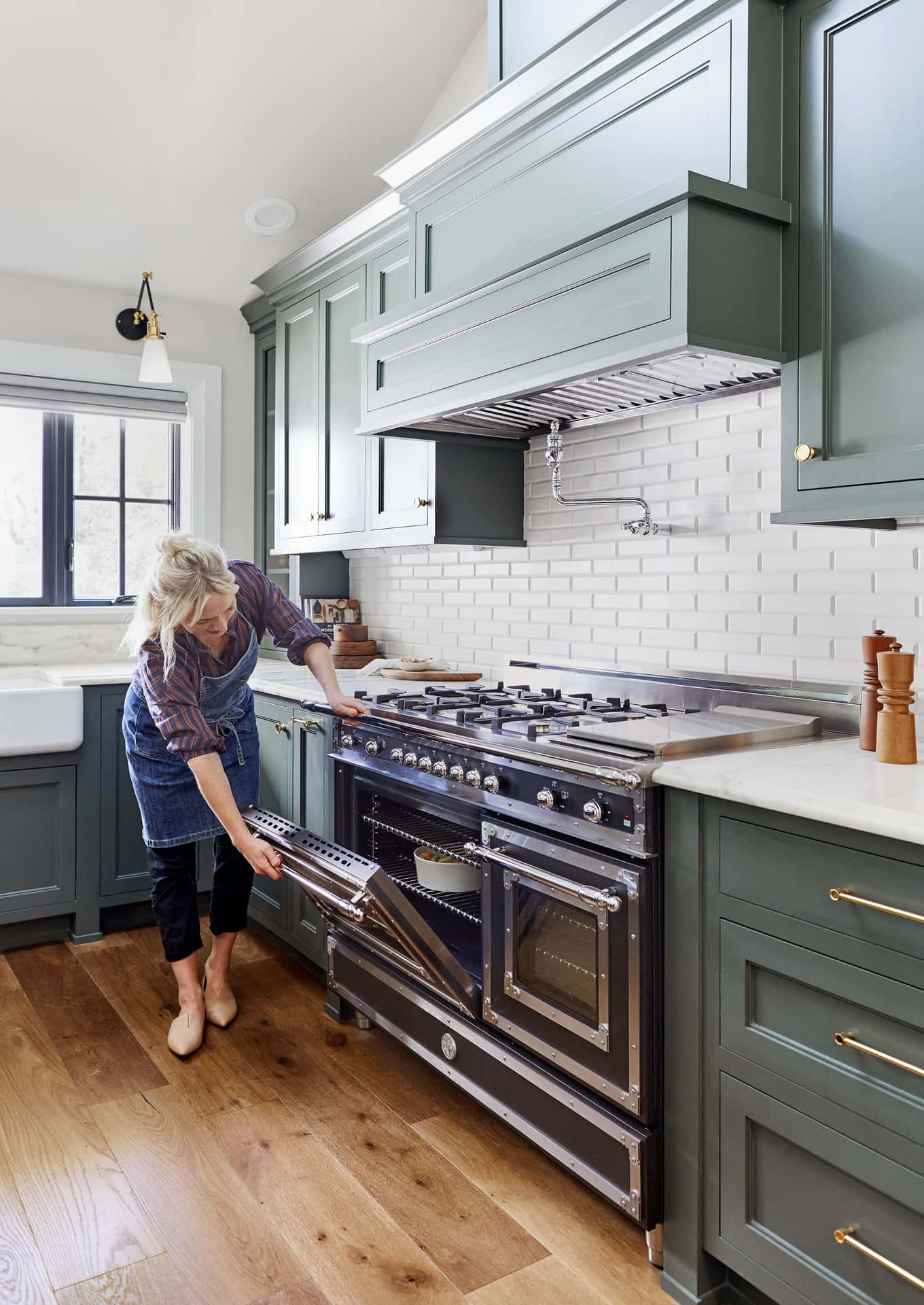A Woman Is Putting A Green Oven In A Kitchen