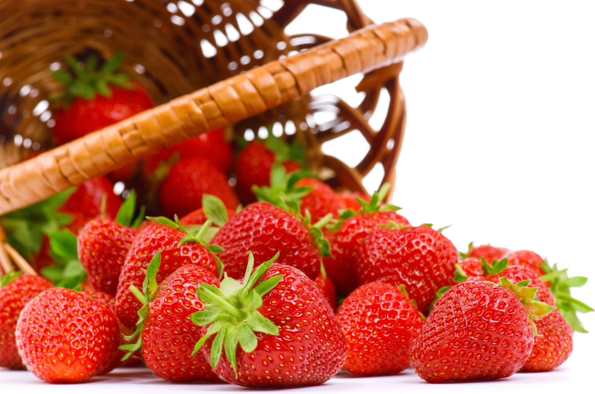 Fresh strawberries tumbling from a wicker basket Wallpaper