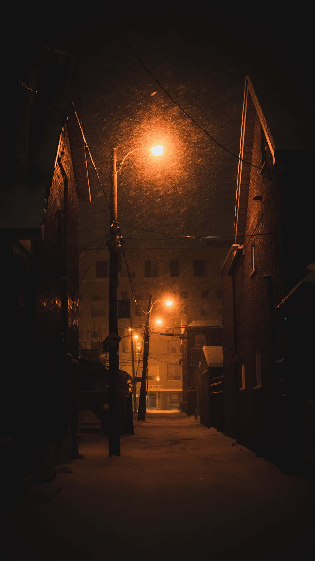 Udsyn om natten til en stille gade oplyst af elektriske gadelygter Wallpaper