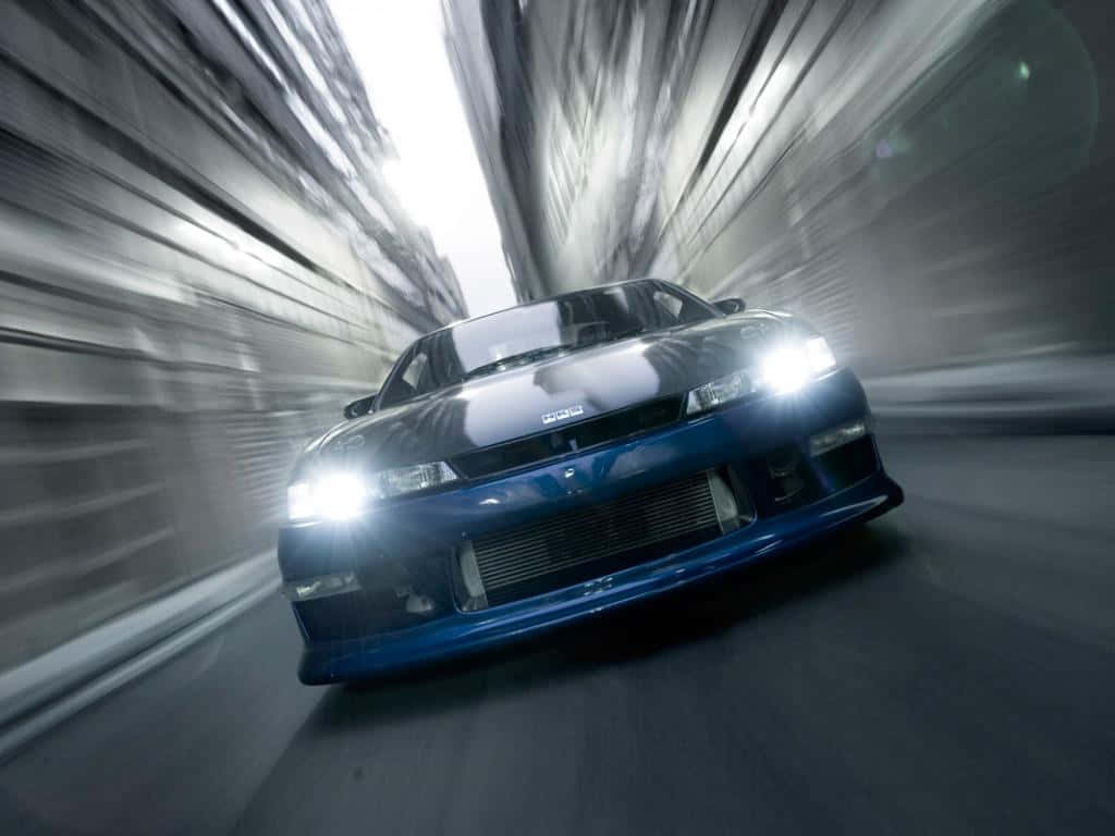 En blå bil kører ned ad en gade i en mørk tunnel. Wallpaper