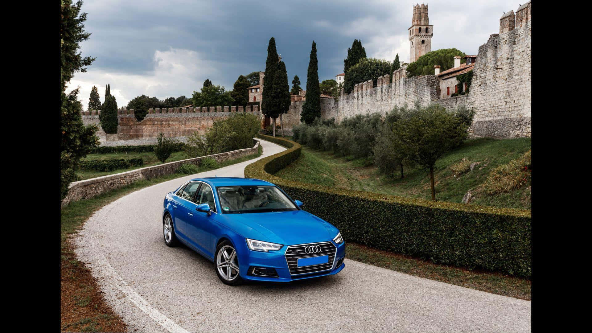 En blå Audi A4 kører ned ad en vej Wallpaper