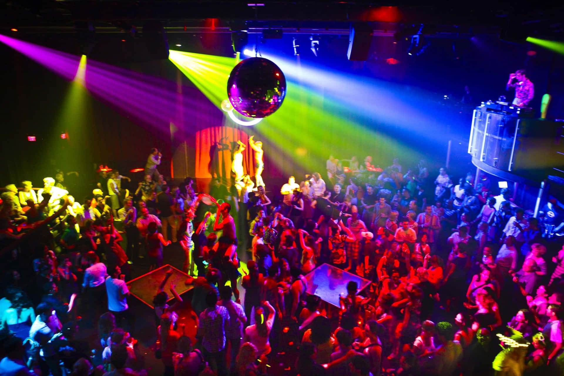 A Crowd Of People At A Nightclub With Colorful Lights