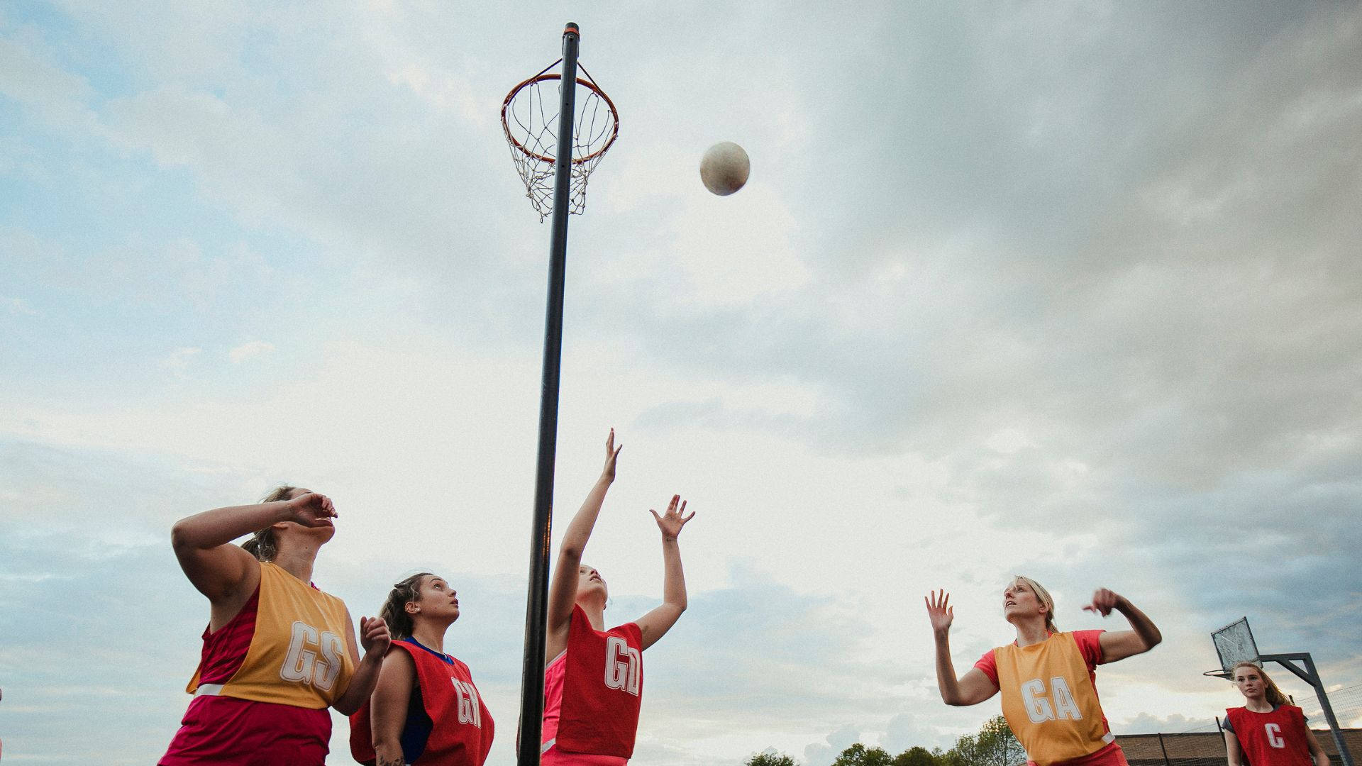 Students Playing Outdoor Netball Catch Ball Wallpaper
