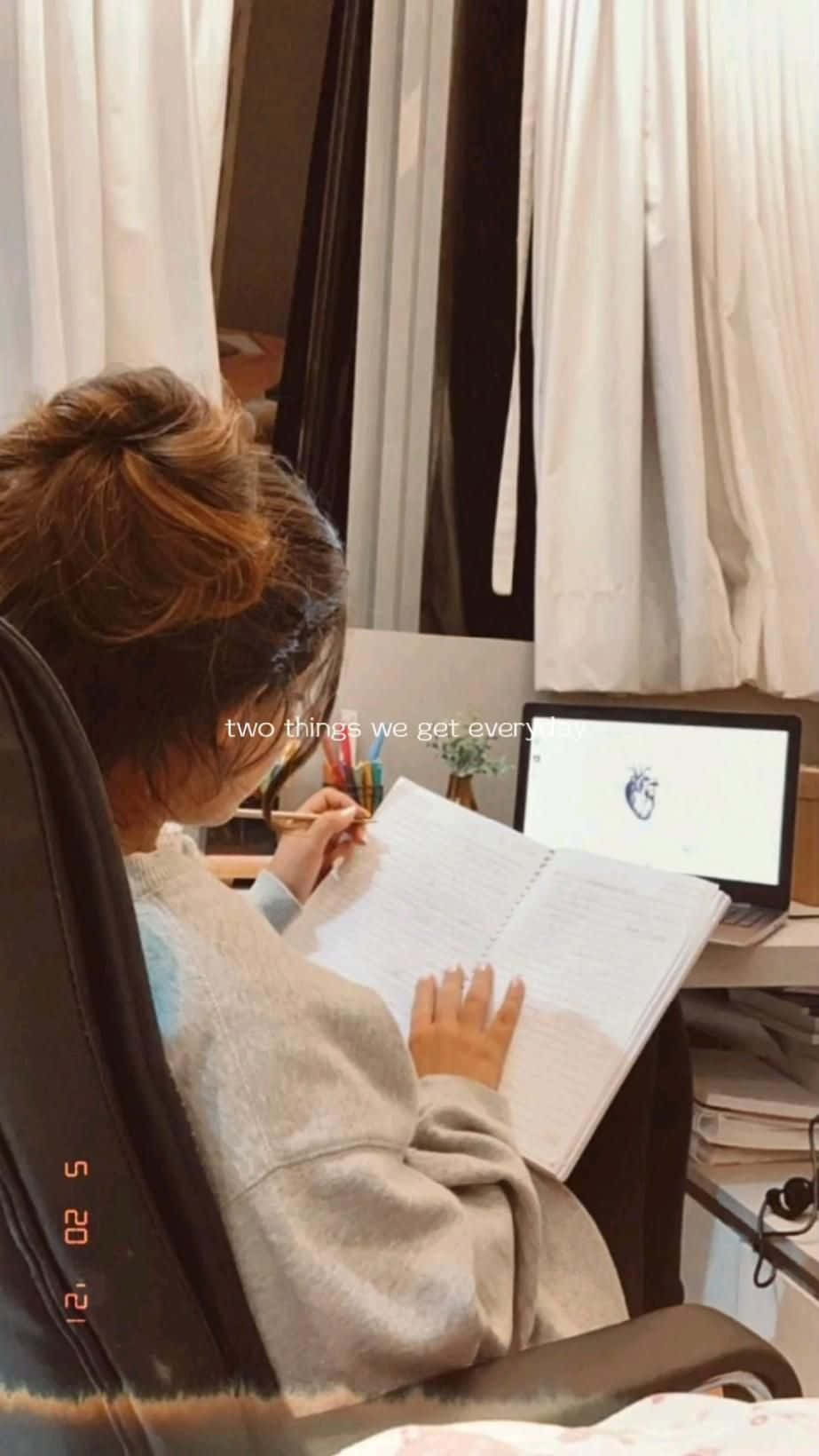 A Woman Is Sitting In A Chair And Writing On A Laptop