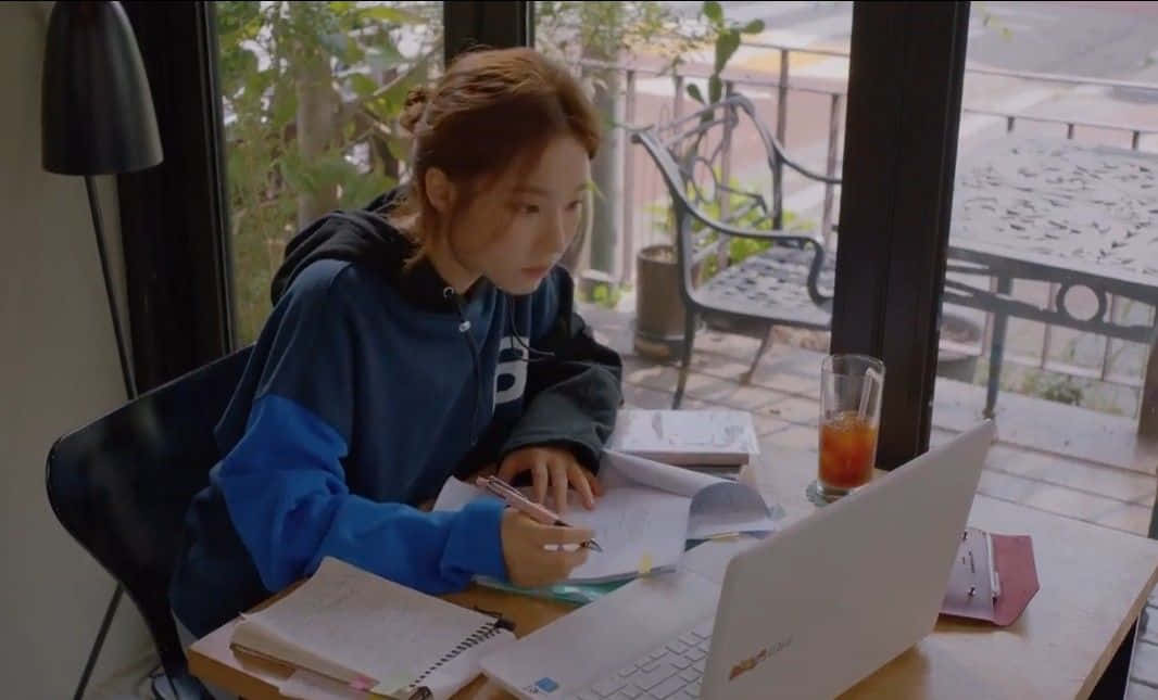 A Girl Is Sitting At A Table With A Laptop