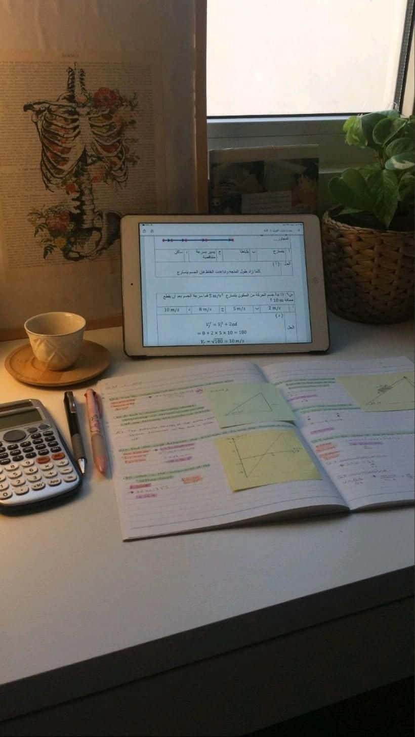 A Desk With A Calculator, Tablet, And A Plant
