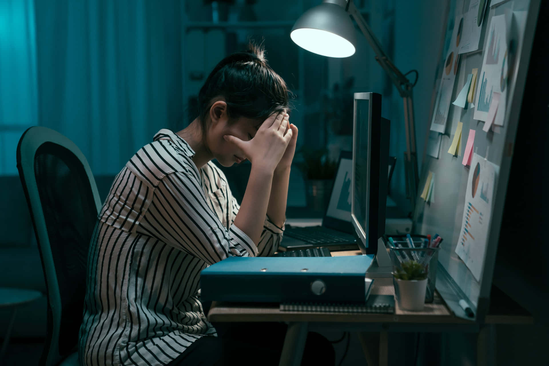 A Woman Sitting At Her Desk At Night