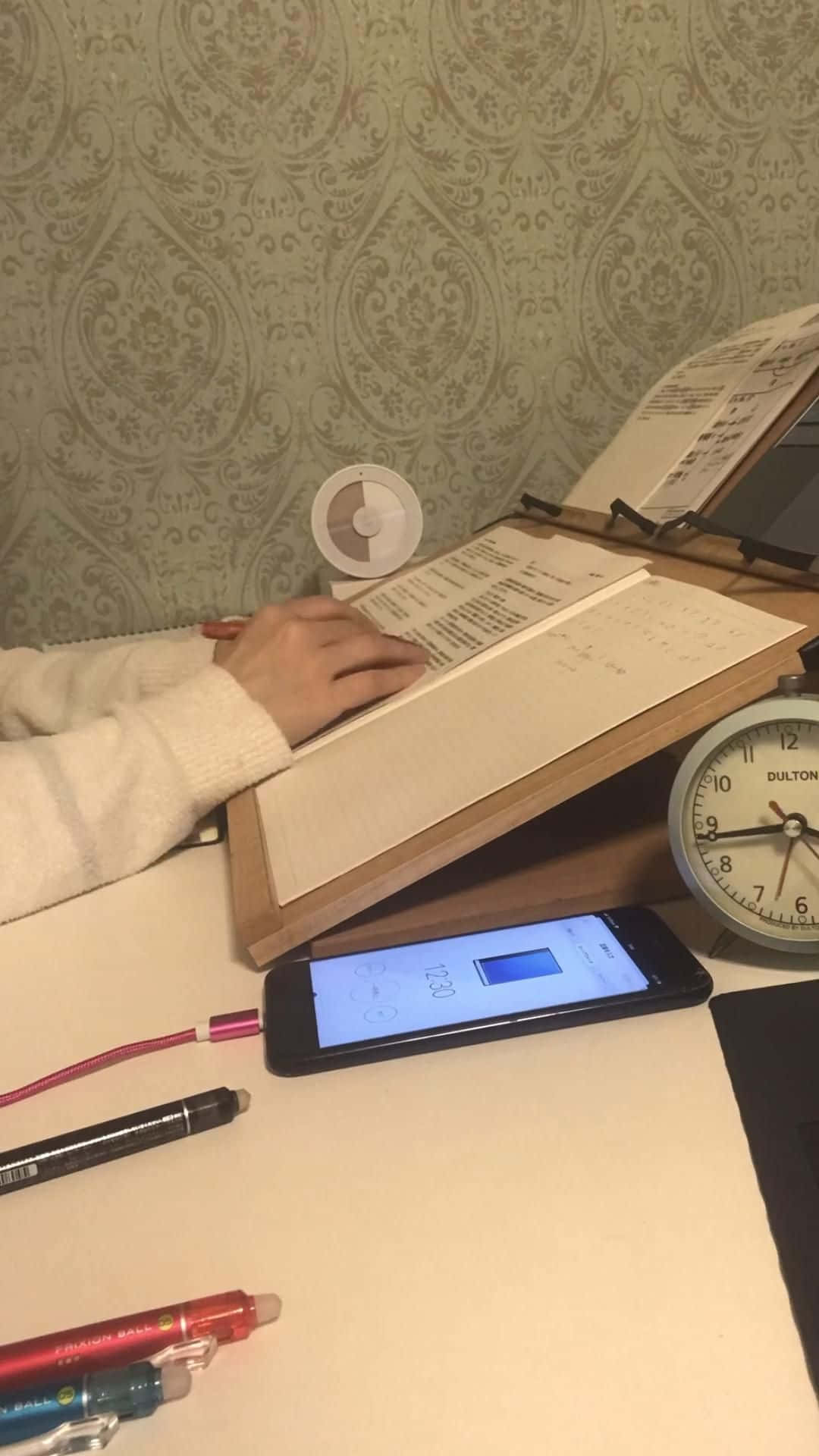 A Woman Is Sitting At Her Desk With A Phone And A Notebook