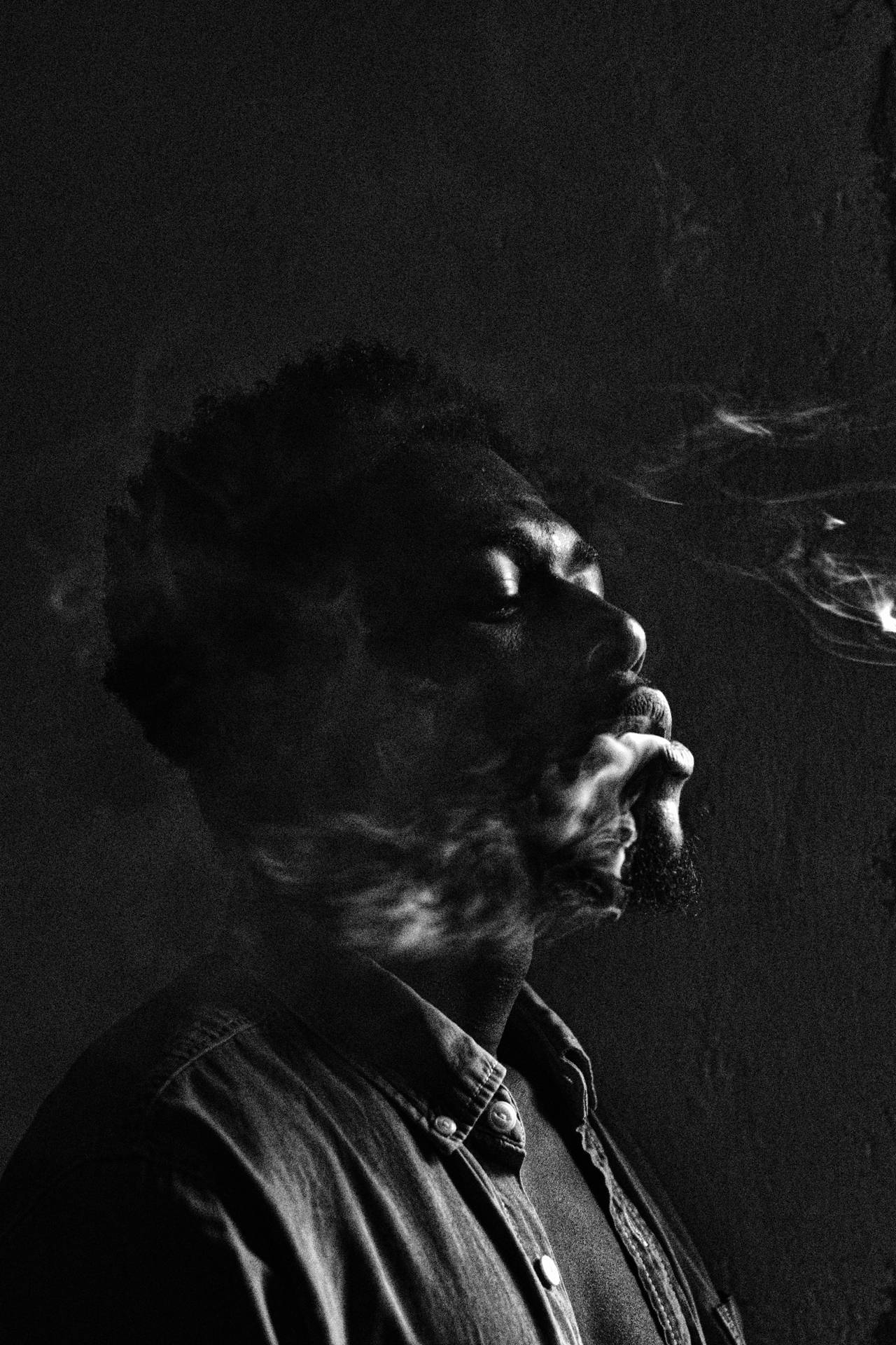 Stilfuld sort skægget mand, der ryger en cigar i det mørke rum Wallpaper