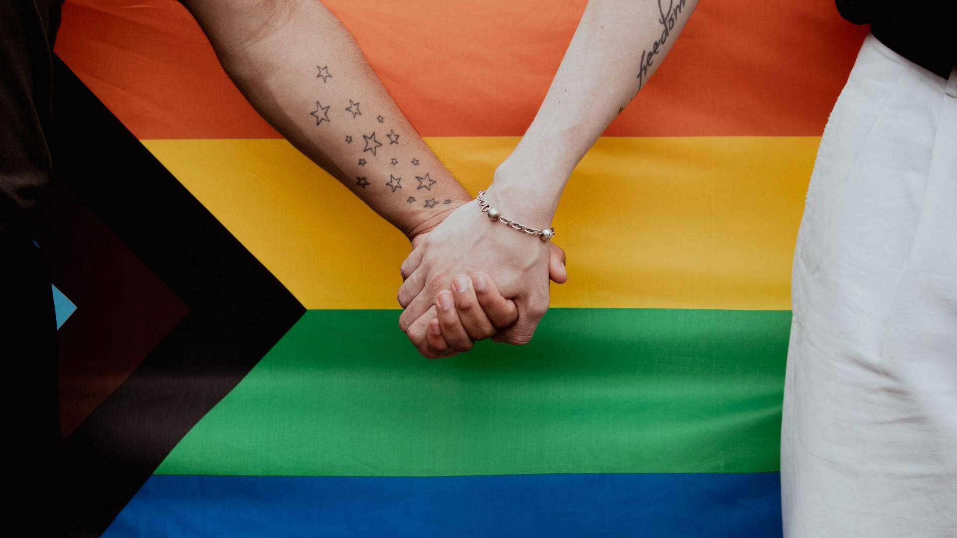 To personer holder i hænder foran et regnbue flag Wallpaper