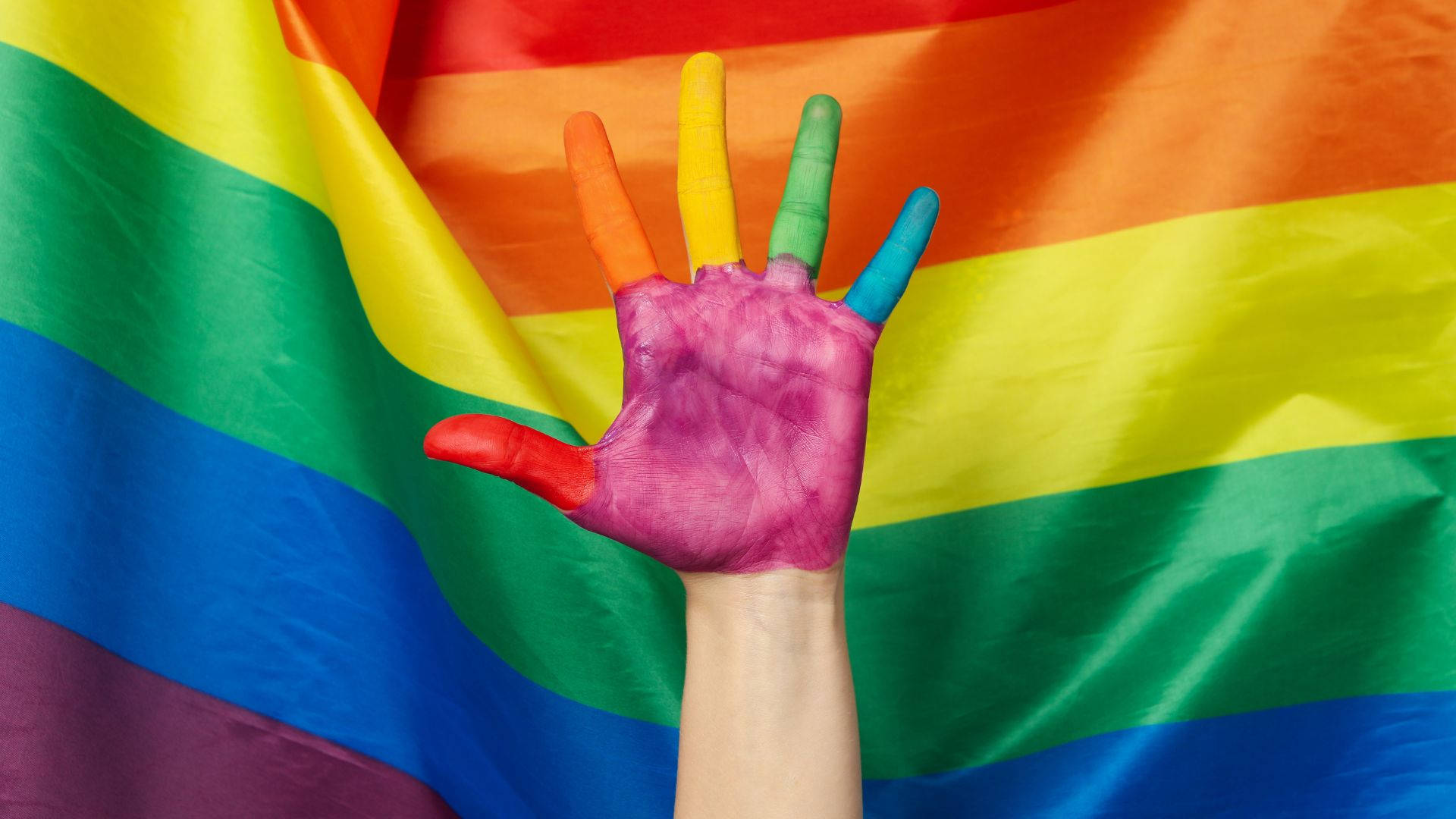 Einehand Einer Frau, Die Mit Regenbogenfarben Bemalt Ist, Wird Vor Einer Regenbogenflagge Hochgehalten. Wallpaper