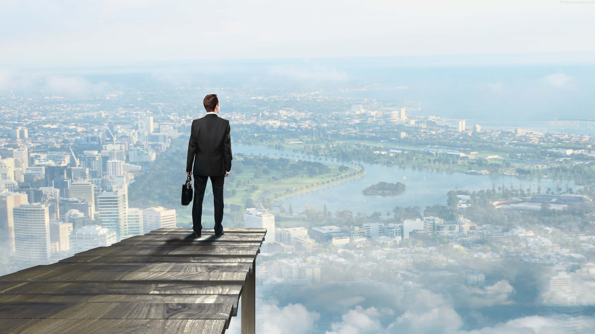 A Man Standing On A Ledge Overlooking A City