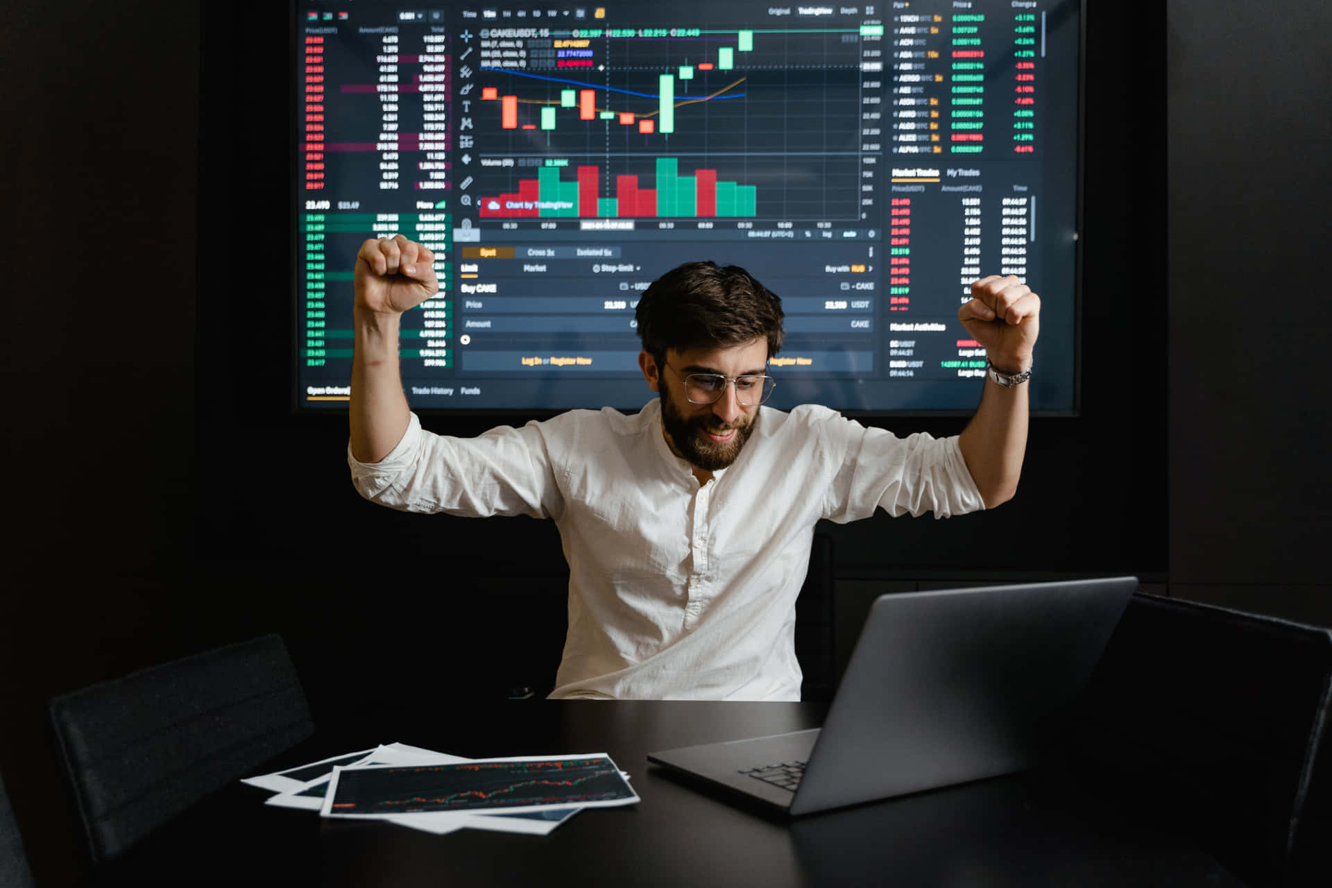 Successful Trader Celebratingin Frontof Stock Market Monitors.jpg Wallpaper