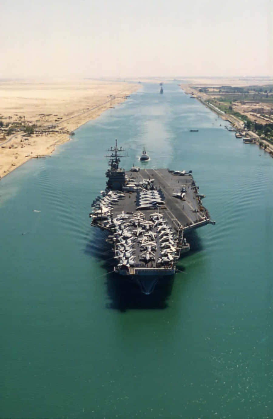 An Aircraft Carrier Is Traveling Down A River