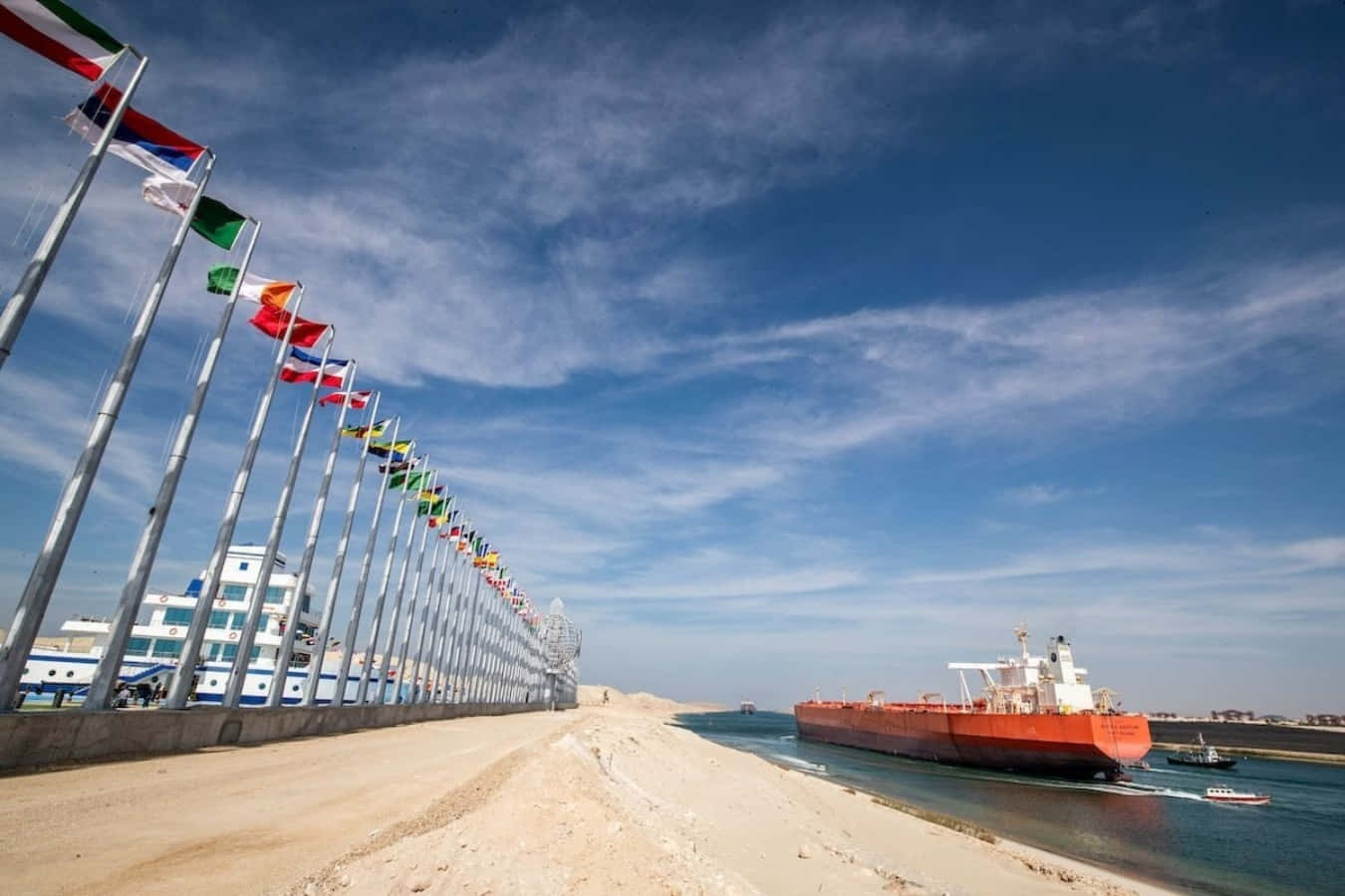A Ship Is Docked Next To Flags On The Shore