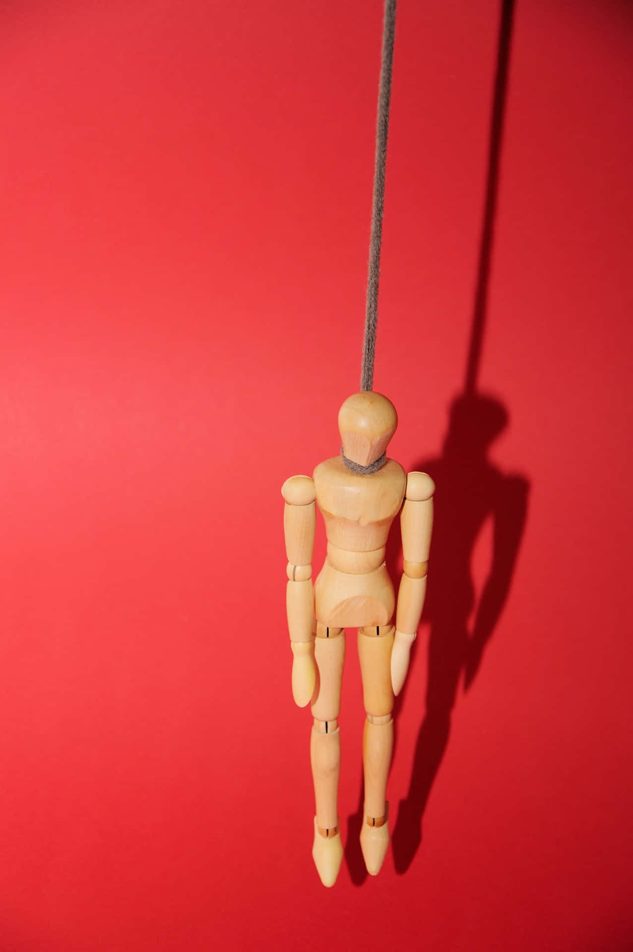 A Wooden Mannequin Hanging From A String Wallpaper