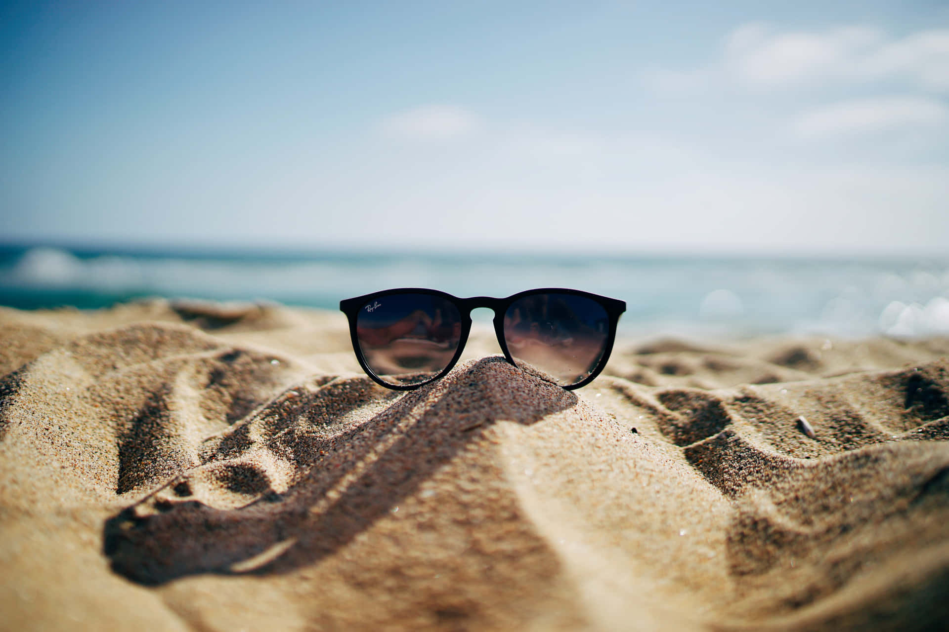 A Pair Of Sunglasses On The Sand Wallpaper