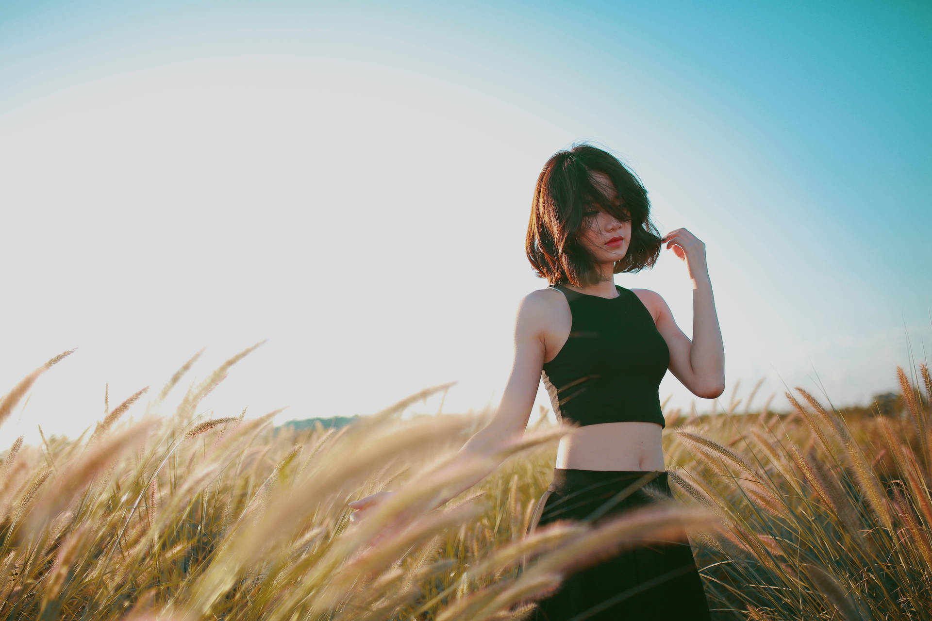 A lonely girl walking in a sunlit field Wallpaper