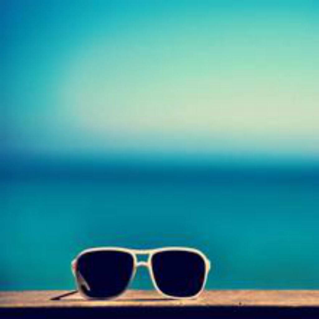 Sunglasses On A Wooden Deck With The Ocean In The Background Wallpaper