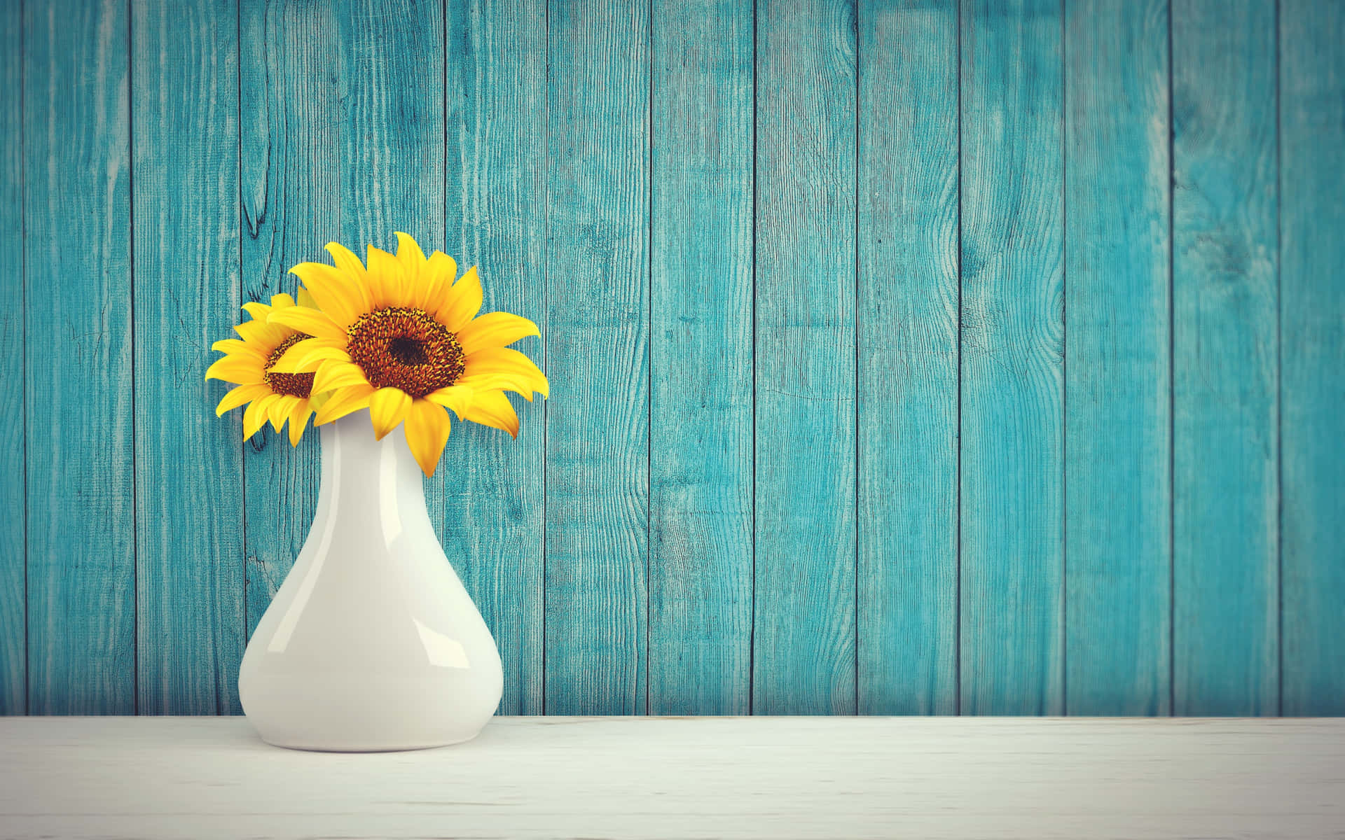 a white vase with sunflowers on a wooden table