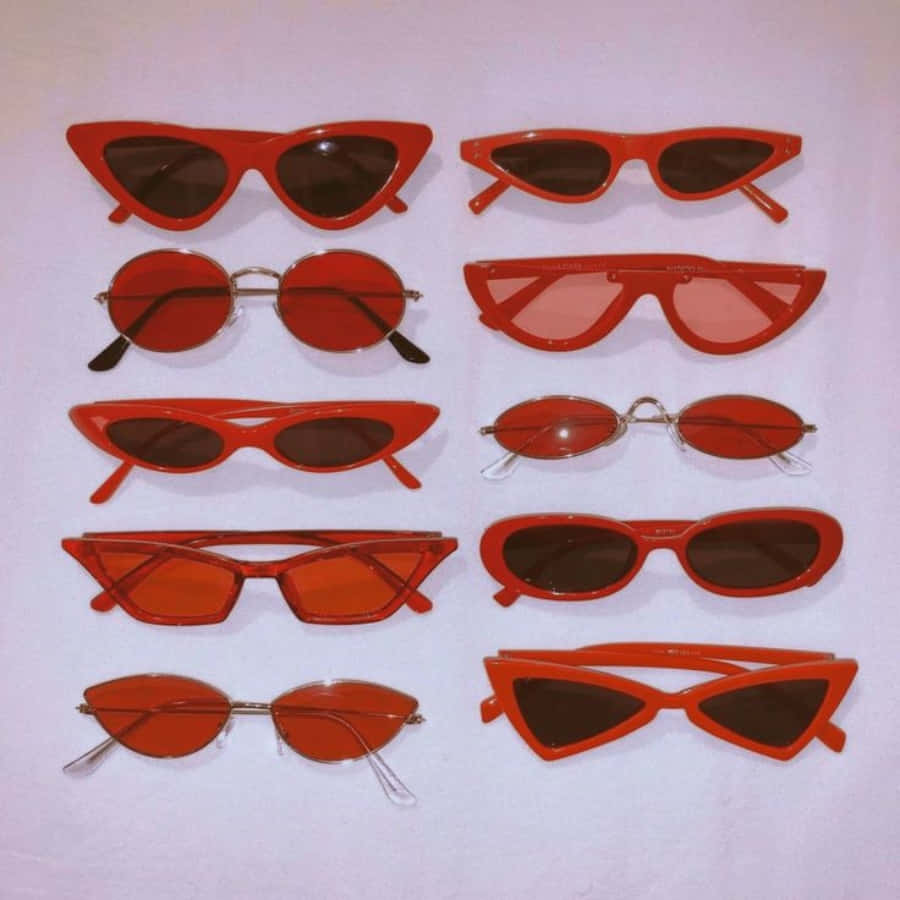A Group Of Red Sunglasses Are Arranged On A White Surface
