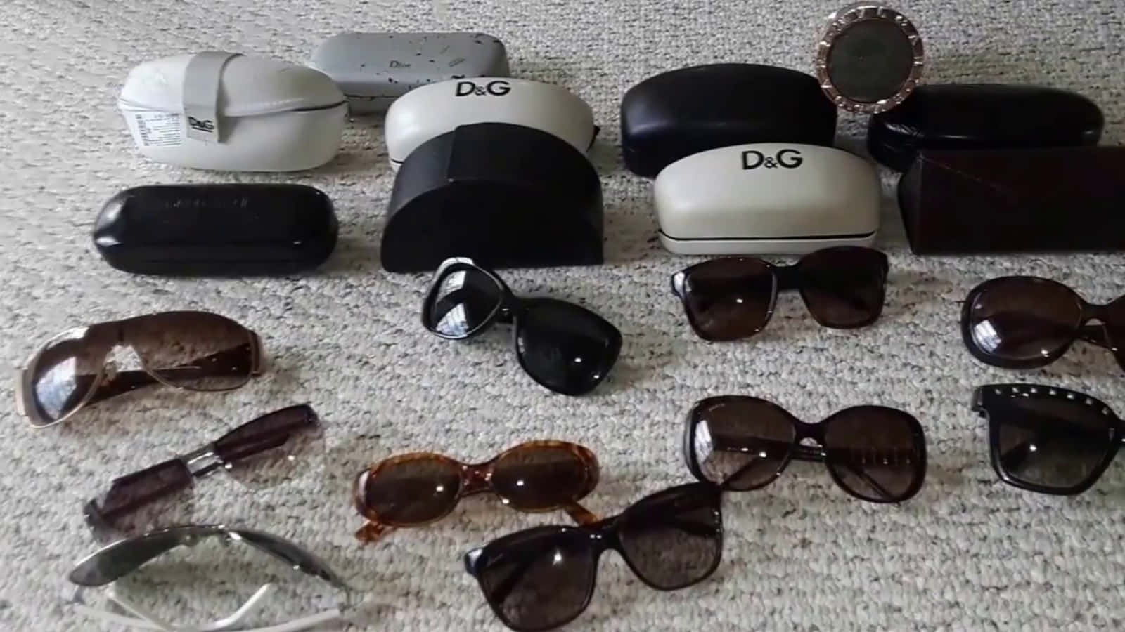 A Group Of Sunglasses And Cases Are Laid Out On A Carpet
