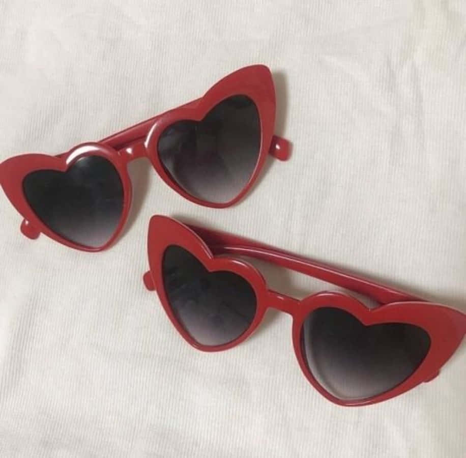 Two Red Heart Shaped Sunglasses On A White Bed