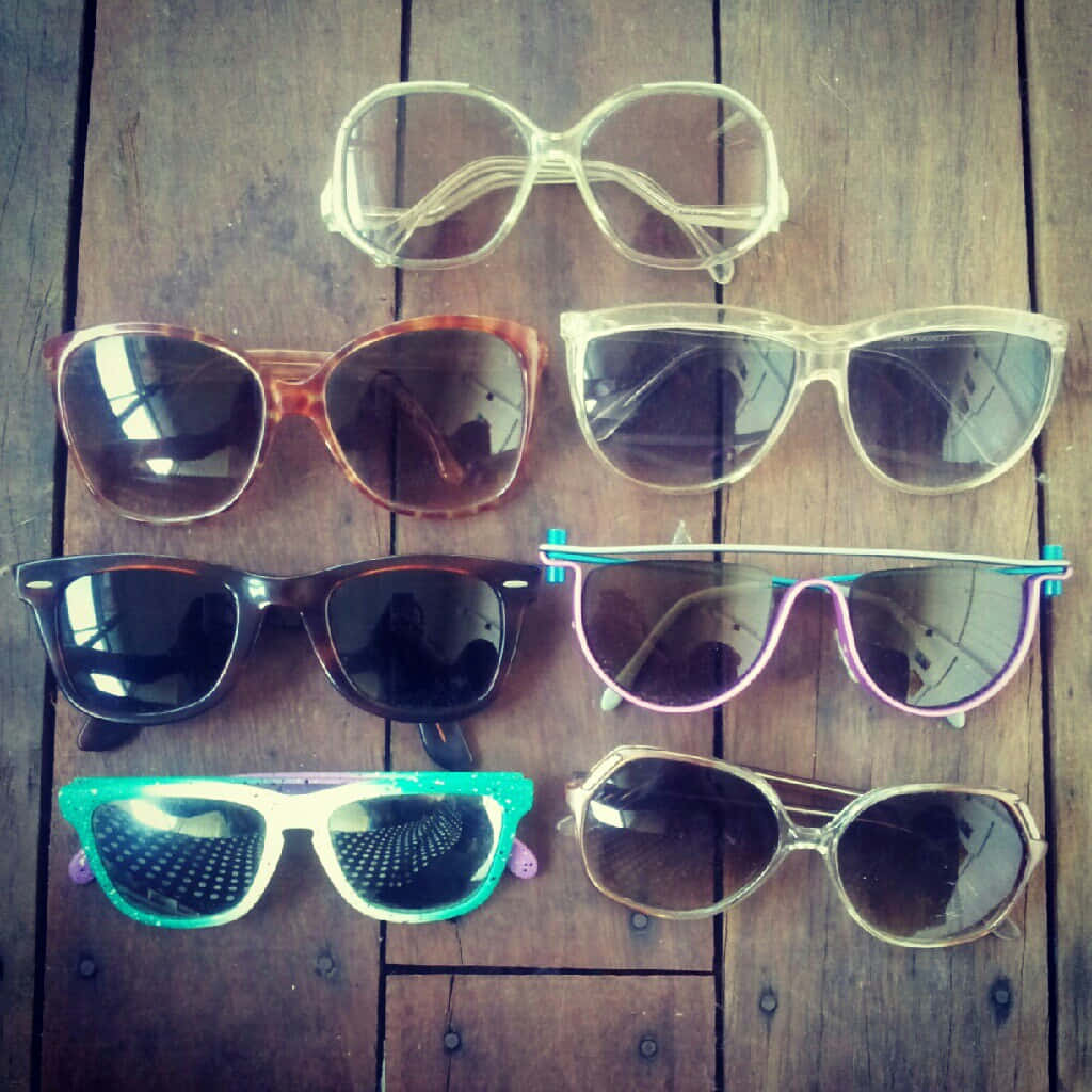 A Group Of Sunglasses Laying On A Wooden Floor