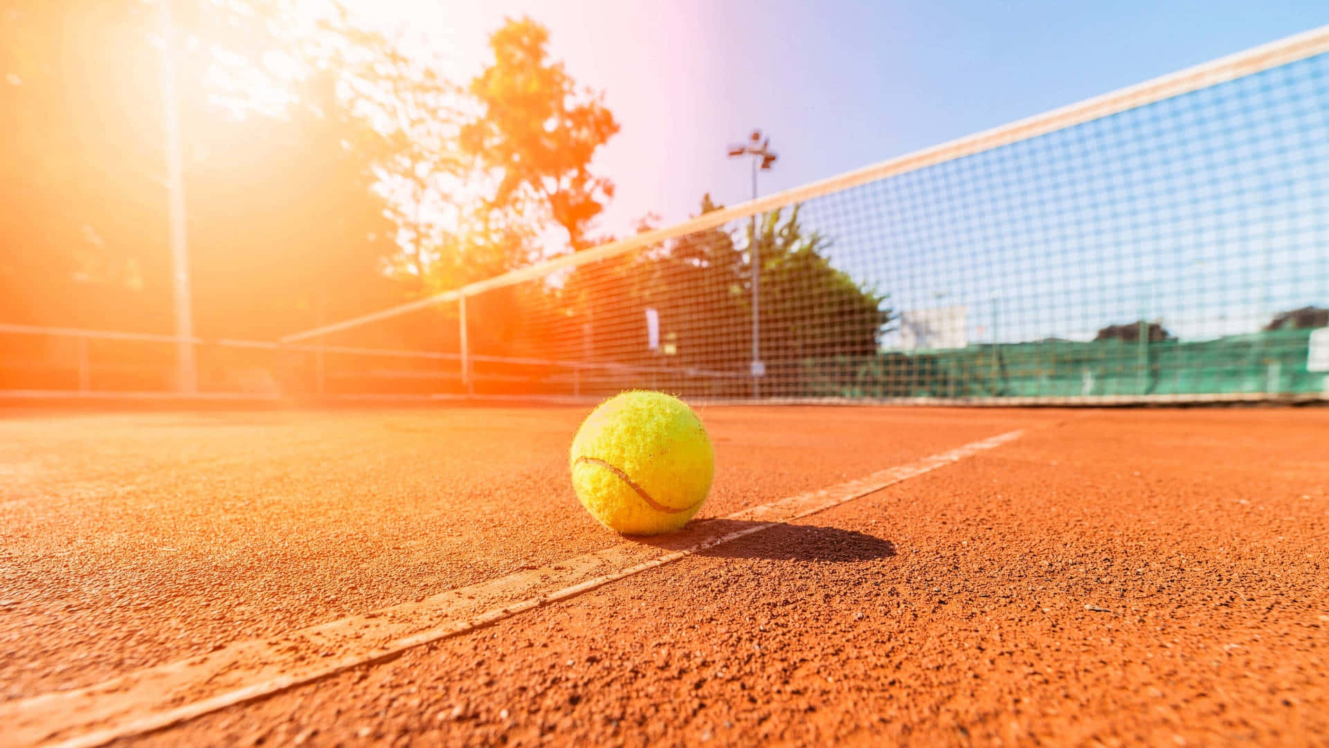 Sunlit Tennis Courtwith Ball.jpg Wallpaper