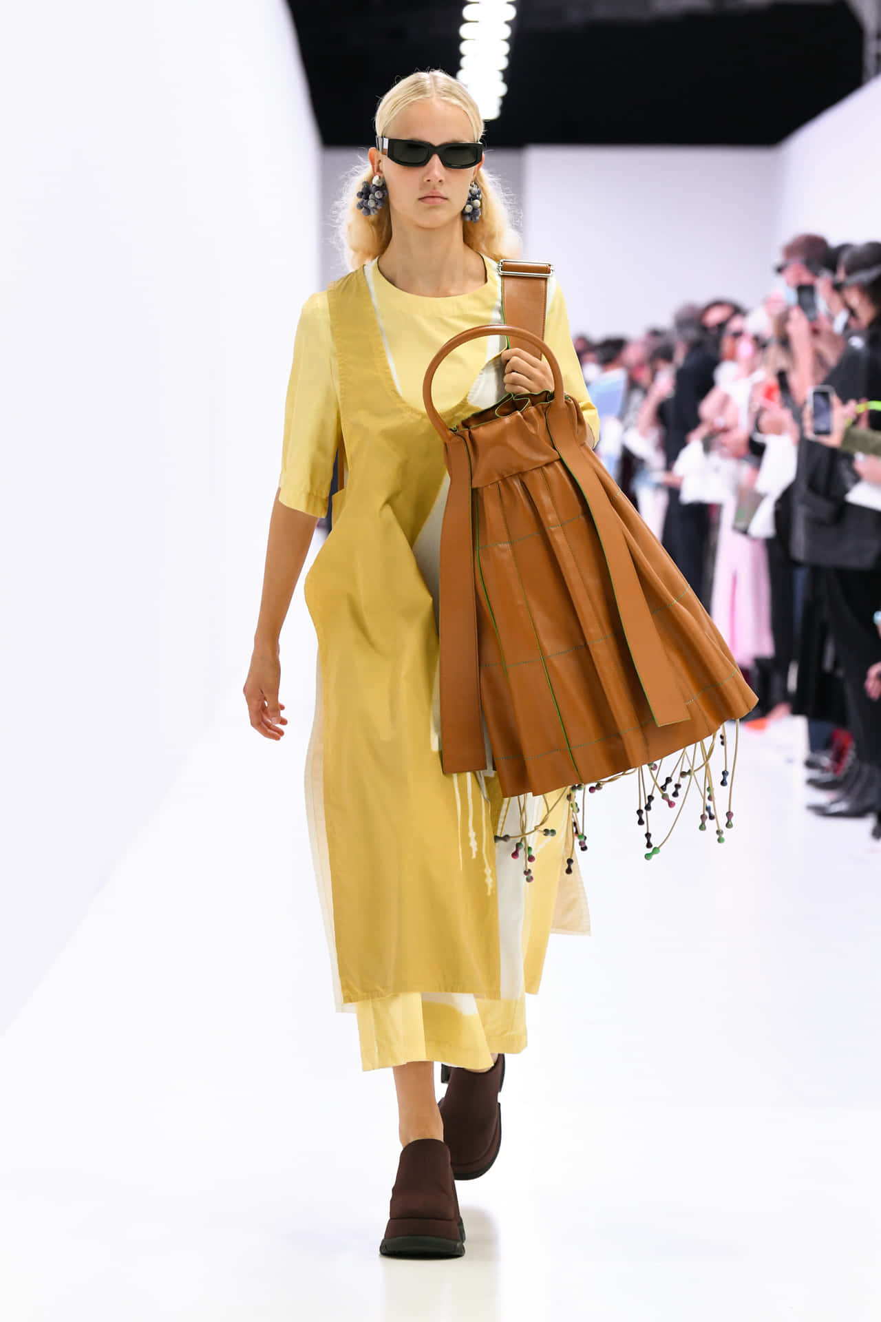 Sunnei Model With Yellow Outfit And Brown Bag Wallpaper