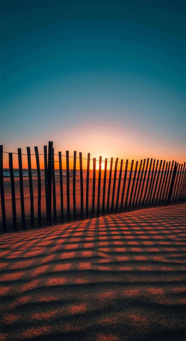 A Fence In The Sand At Sunset Wallpaper