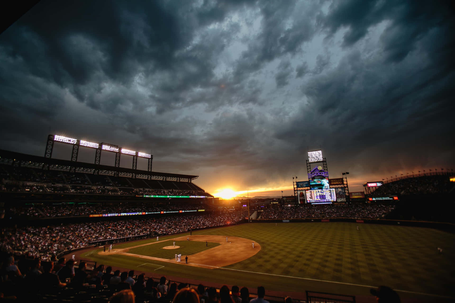 Sunset Baseball Game Under Stormy Skies Wallpaper