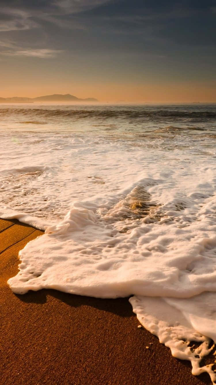 Contemplea Beleza De Um Pôr Do Sol Idílico Na Praia Com O Seu Iphone Para Um Momento Inesquecível. Papel de Parede
