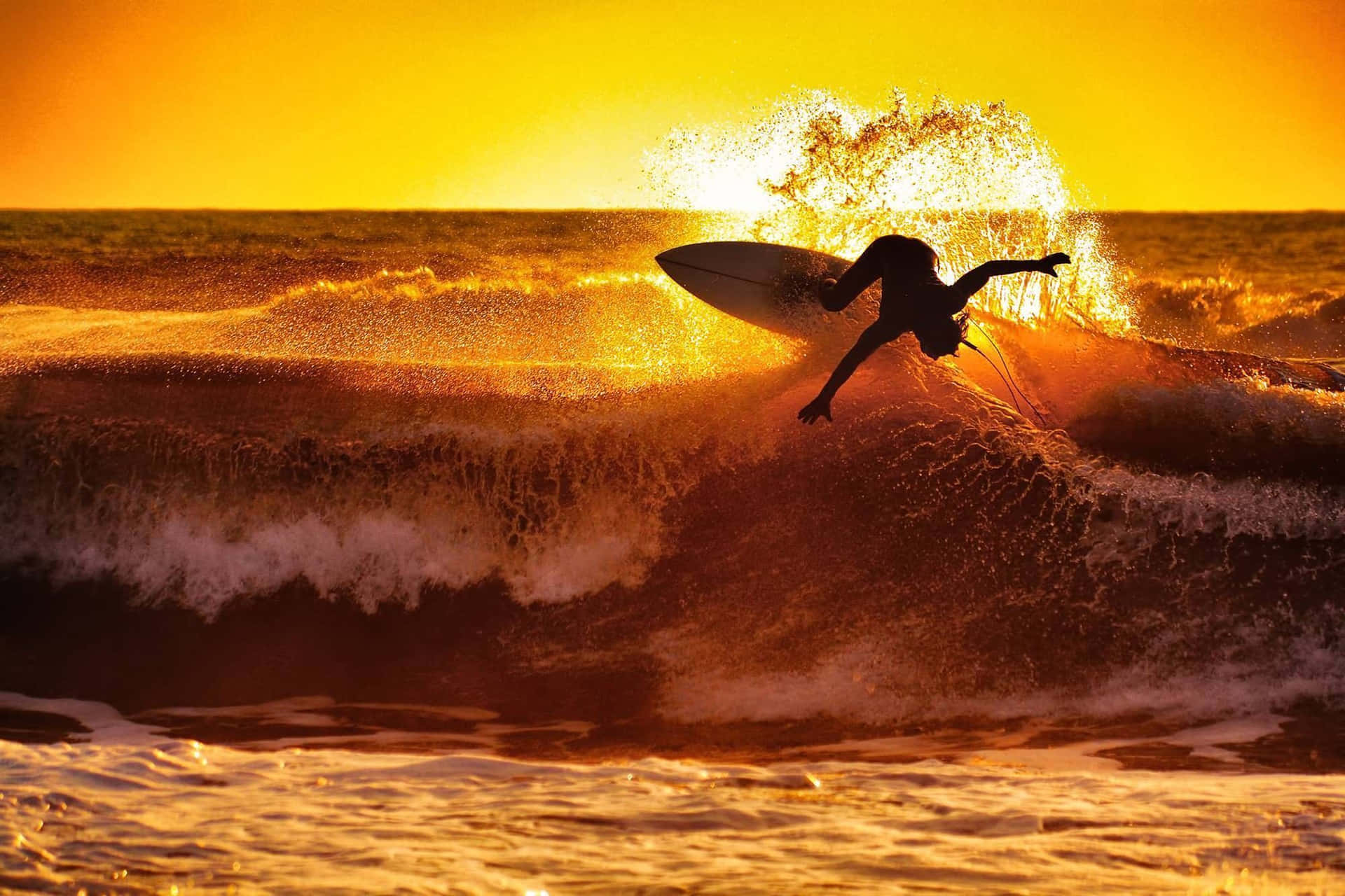 Immaginecon Uno Sfondo Di Un Surfer Che Esegue Una Fantastica Manovra Al Tramonto Sulla Spiaggia.