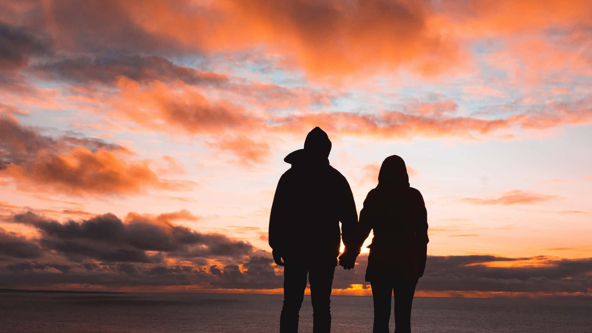 Solnedgångsbildpå Par Som Håller Hand.
