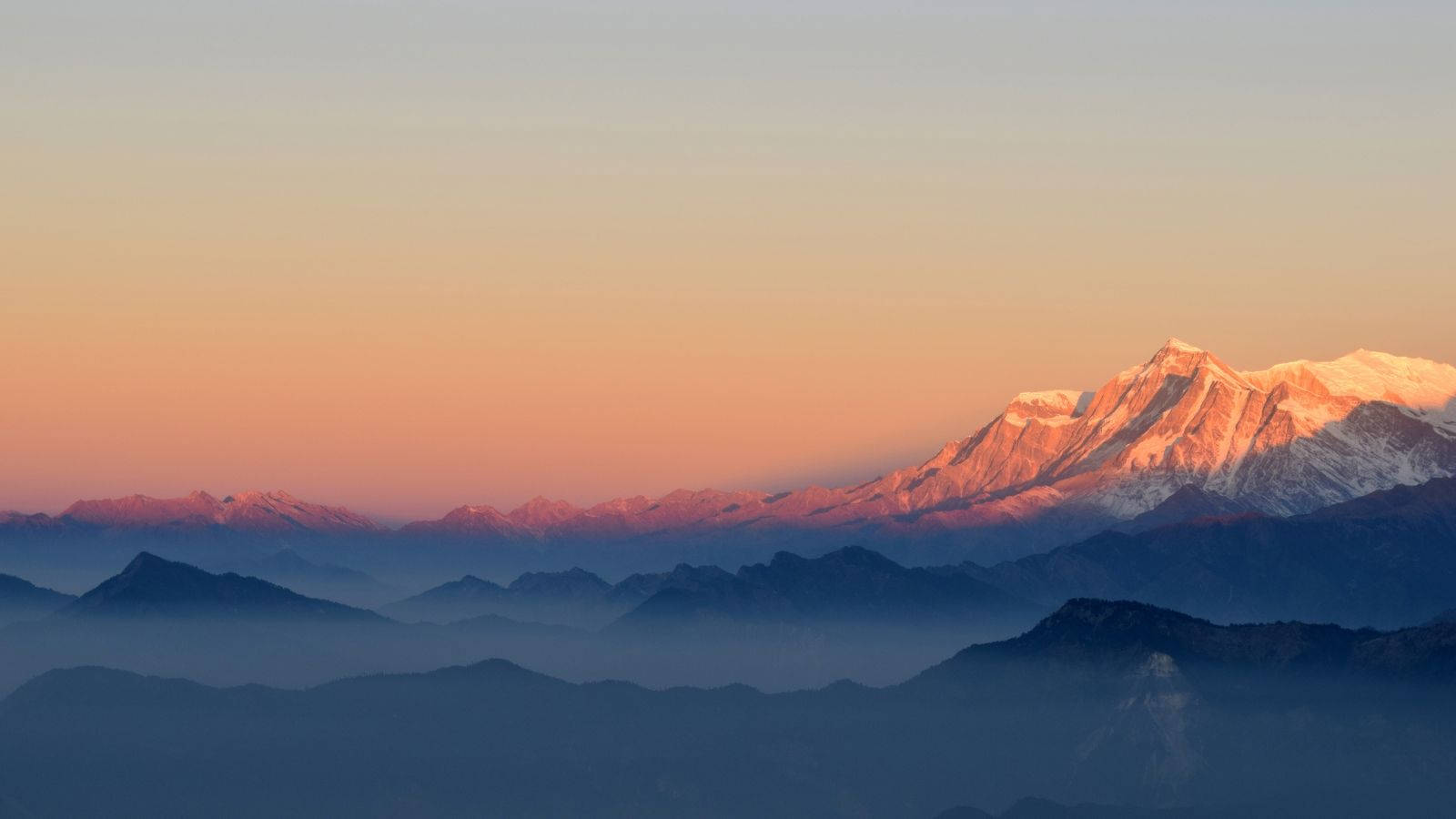 A view of snow-covered mountain ranges during a breathtaking sunset Wallpaper