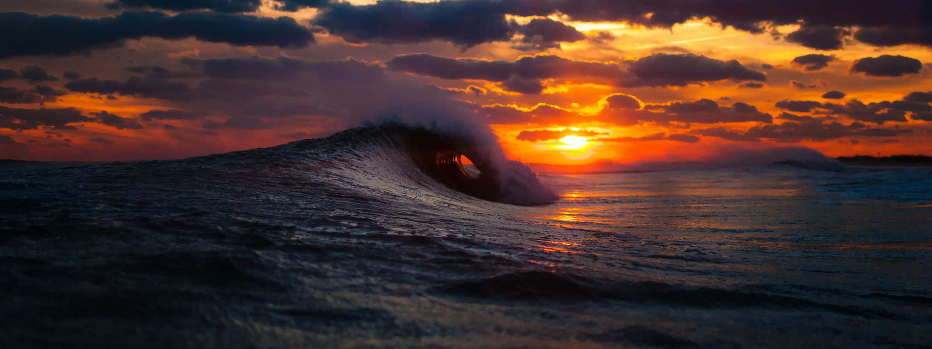 The beauty of a unique sunset reflected in the waves Wallpaper