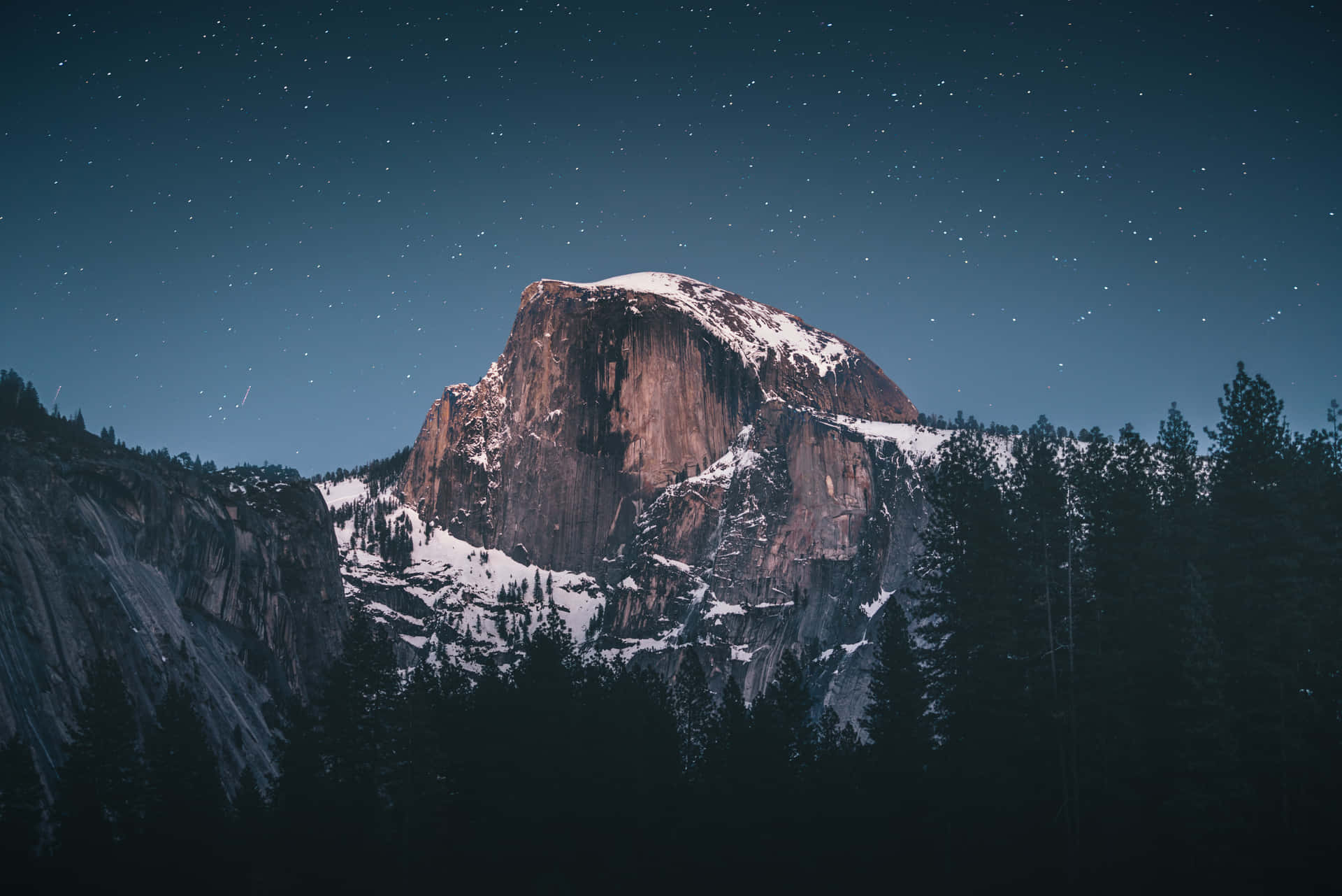 En bjerg ses om natten med stjerner over det Wallpaper
