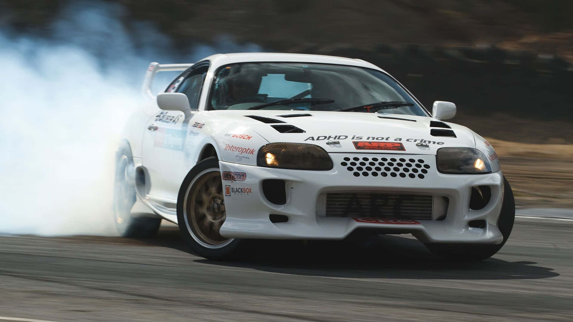 A White Sports Car Is Driving Down A Track With Smoke Coming Out Of It Wallpaper