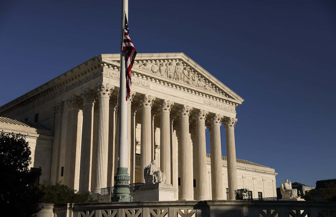 Edificiode La Corte Suprema Con La Bandera Estadounidense. Fondo de pantalla