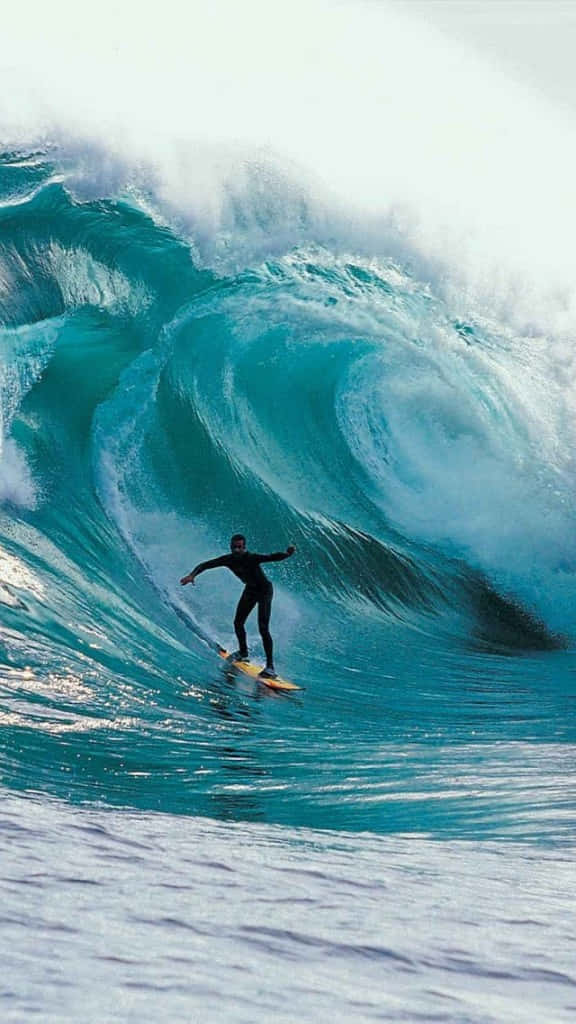 Imagenun Surfista Solitario Atrapando Algunas Olas Mientras Disfruta Del Atardecer Con Su Iphone. Fondo de pantalla