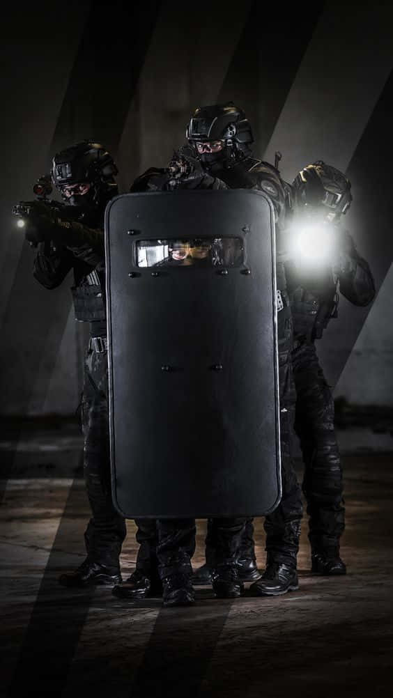 Specialized trained SWAT police units in tactical gear prepared to respond to any situation. Wallpaper